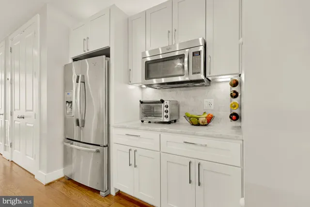 a kitchen with stainless steel appliances white cabinets and a refrigerator