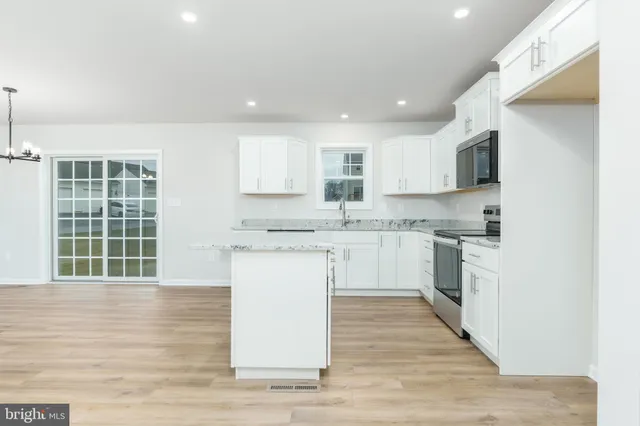 a kitchen with granite countertop white cabinets sink and stainless steel appliances