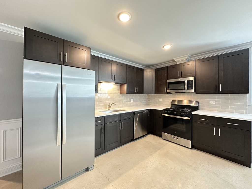 4117 South Michigan Avenue, Unit GS Chicago, IL 60653 - Photo 3 of 20 a kitchen with stainless steel appliances granite countertop a refrigerator a sink a stove a microwave and wooden cabinets