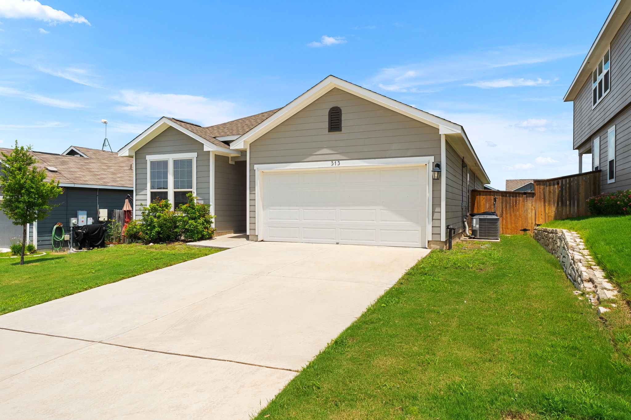 313 Mclintock Road Jarrell, TX 76537 - Photo 2 of 40 A welcoming facade offers a generous driveway leading to a two-car garage, framed by lush green lawns.