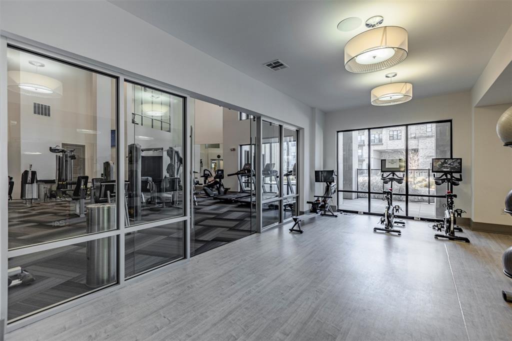 2700 Old Denton Road, Unit 1044 Carrollton, TX 75007 - Photo 27 of 33 Dedicated fitness area featuring wood-finish flooring, ample natural light from extensive glazing, and contemporary drum pendant lighting