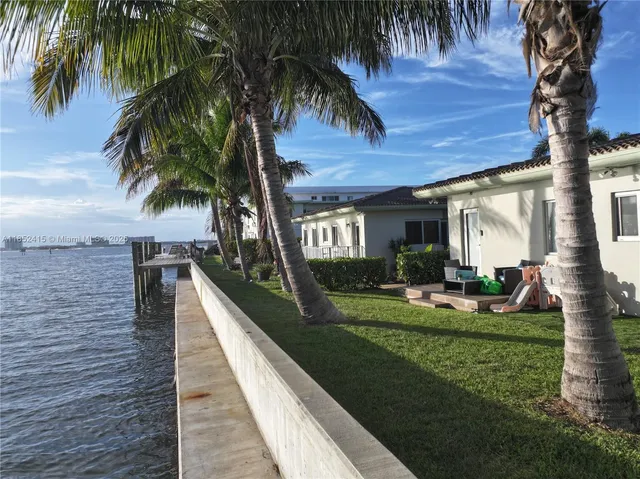a view of a house with a yard and palm trees