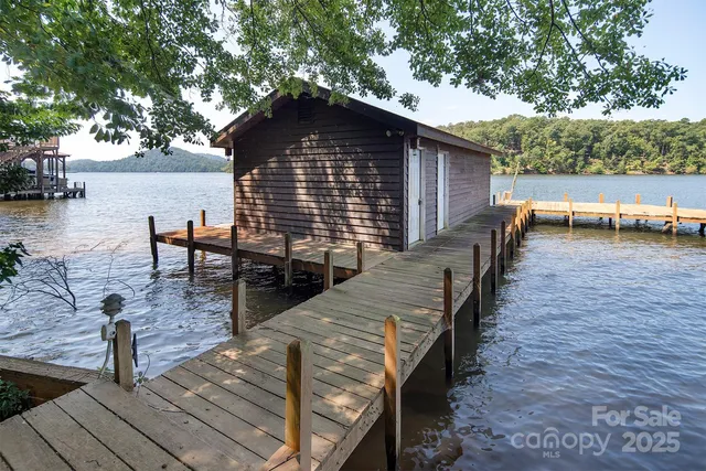 a view of a roof deck with table and chairs a barbeque with wooden floor and fence