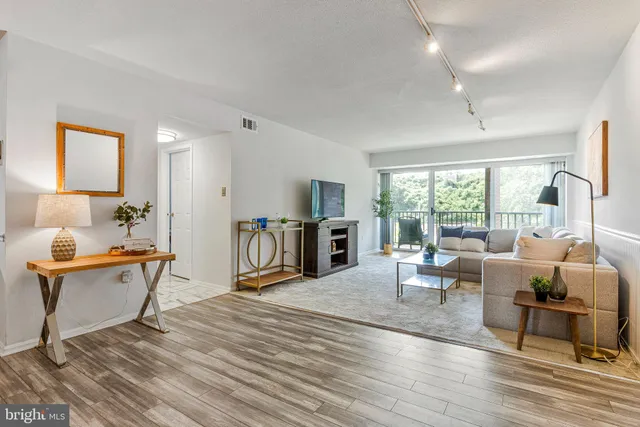 a living room with furniture large window and wooden floor