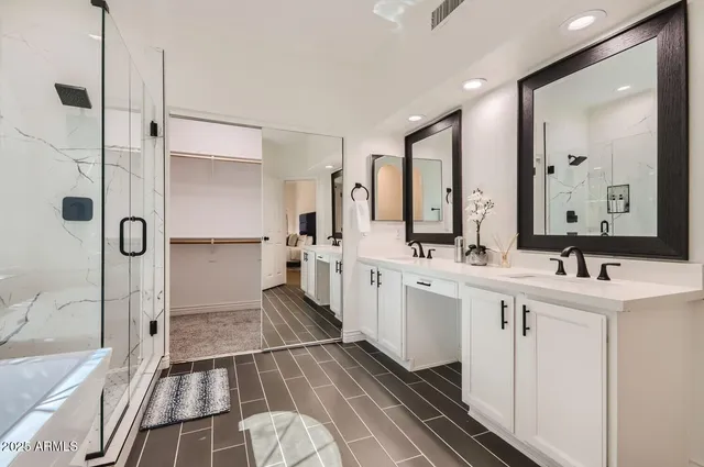 a large white bathroom with a double vanity sink a mirror and a shower