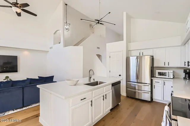 a kitchen with stainless steel appliances sink a refrigerator and wooden floor