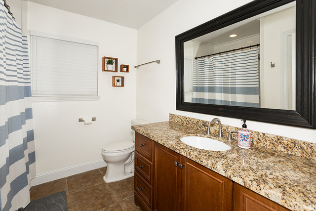 7797 North Windhover Road Eagle Mountain, UT 84005 - Photo 17 of 33 Bathroom featuring an expansive vanity with a light-colored stone countertop, an undermount sink, and wood-finish cabinetry