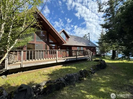 a view of a house with wooden deck and a yard with green space