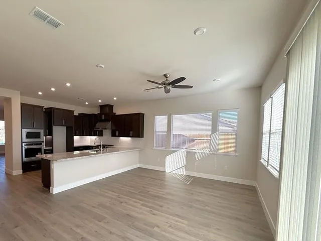 an open kitchen view with wooden floor and stainless steel appliances