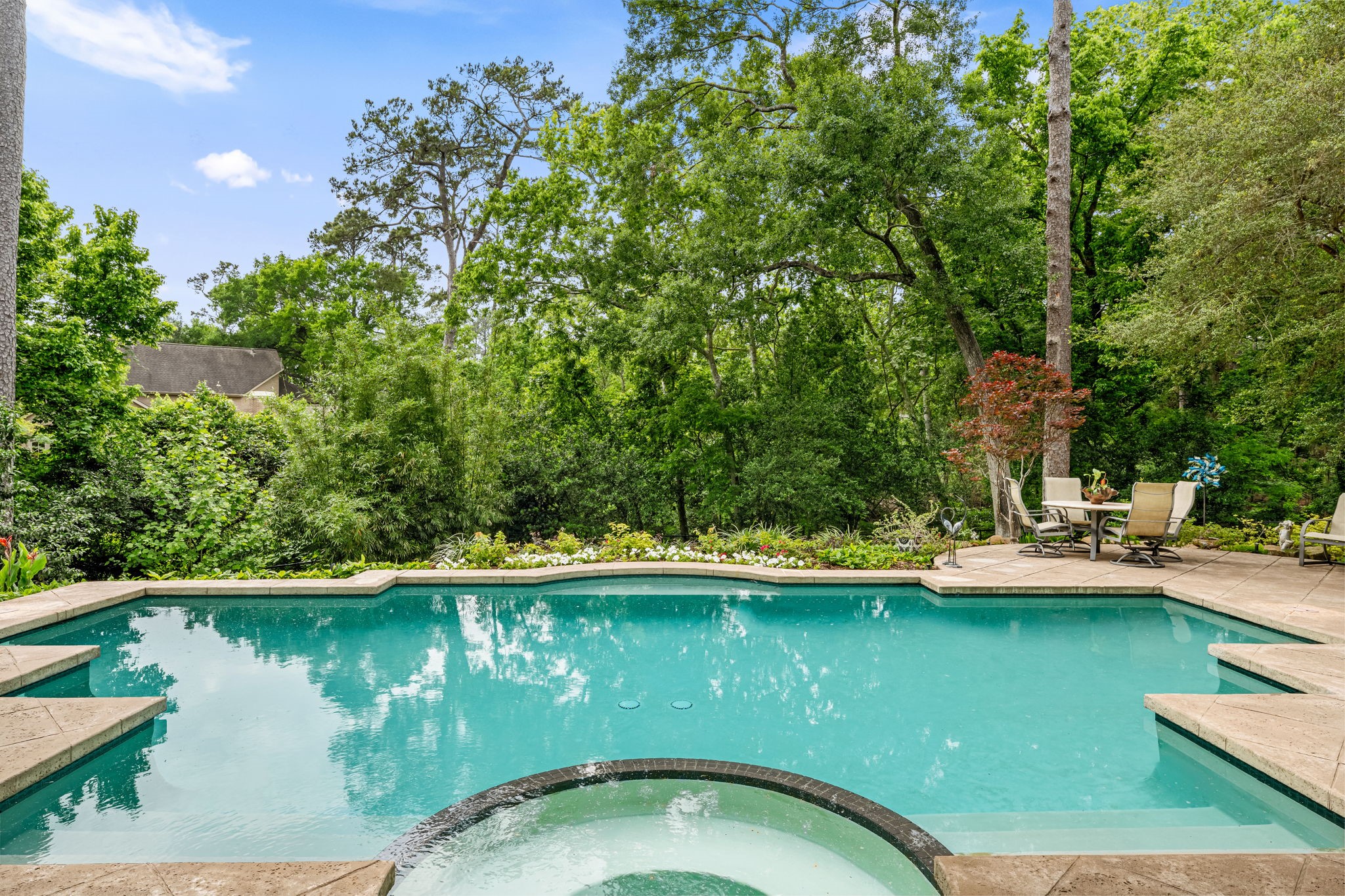 6 Mott Lane Houston, TX 77024 - Photo 9 of 50 Resort-style pool with integrated spa, surrounded by lush greenery and mature trees, offering a private and tranquil outdoor retreat.