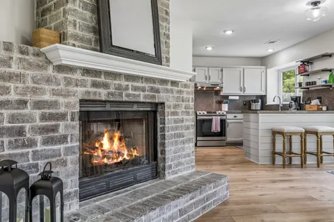 a open kitchen with granite countertop a stove top oven a sink dishwasher and a fireplace with wooden floor