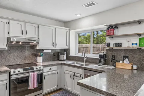 a kitchen with stainless steel appliances granite countertop a sink stove and cabinets