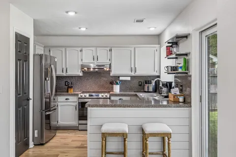 a kitchen with stainless steel appliances granite countertop a refrigerator and a stove top oven