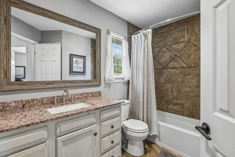 a bathroom with a granite countertop sink toilet and shower