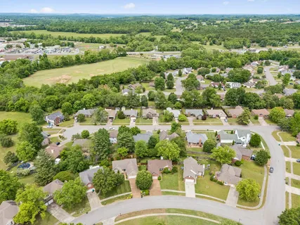 an aerial view of residential houses with outdoor space and trees