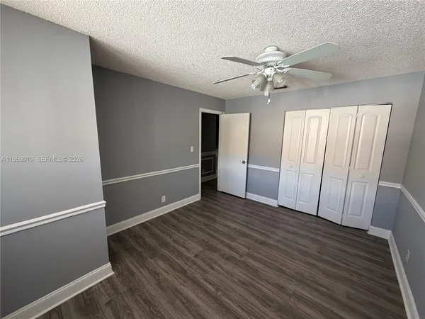 an empty room with wooden floor fan and windows