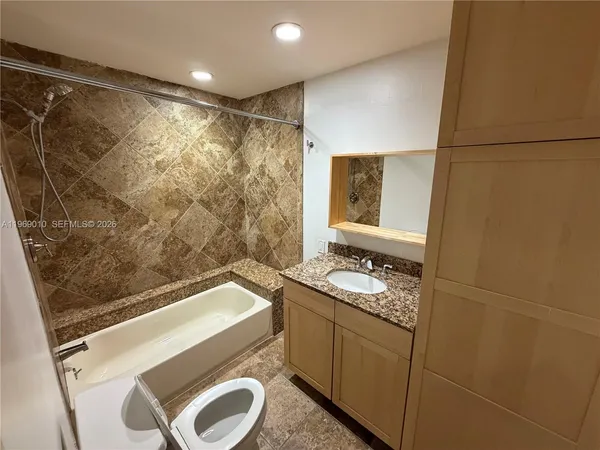 a bathroom with a granite countertop sink toilet and shower