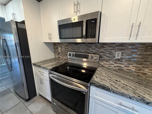 a kitchen with granite countertop cabinets stove and microwave