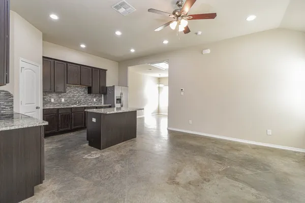 a kitchen with stainless steel appliances kitchen island granite countertop a refrigerator a sink dishwasher a stove with white cabinets