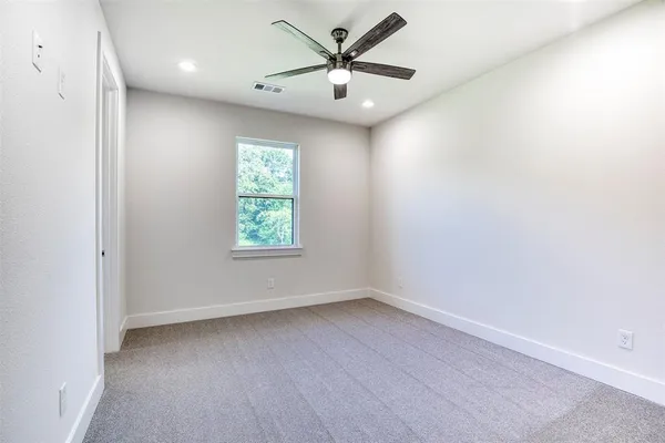 an empty room with a window and a fan