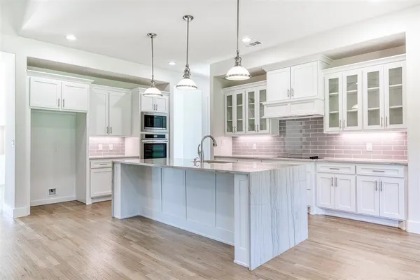 a kitchen with stainless steel appliances granite countertop a sink a oven a refrigerator and white cabinets