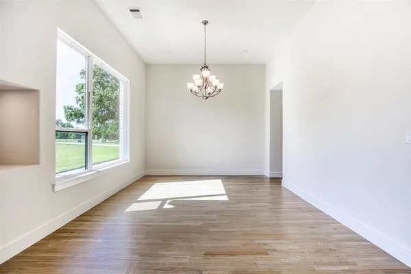 a view of a livingroom with wooden floor a chandelier and a window