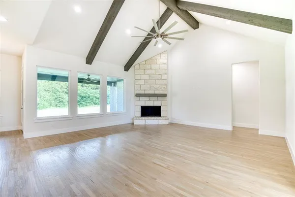 an empty room with wooden floor fan and windows