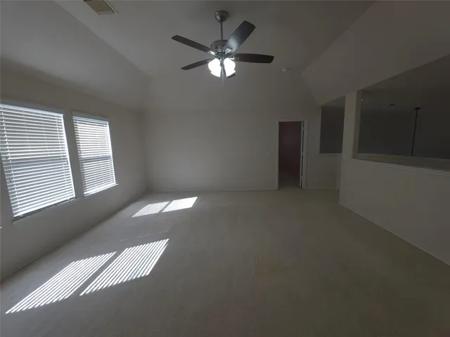 an empty room with windows and ceiling fan