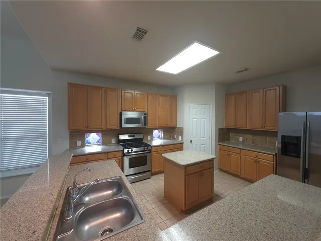 an empty room with a fireplace and chandelier fan