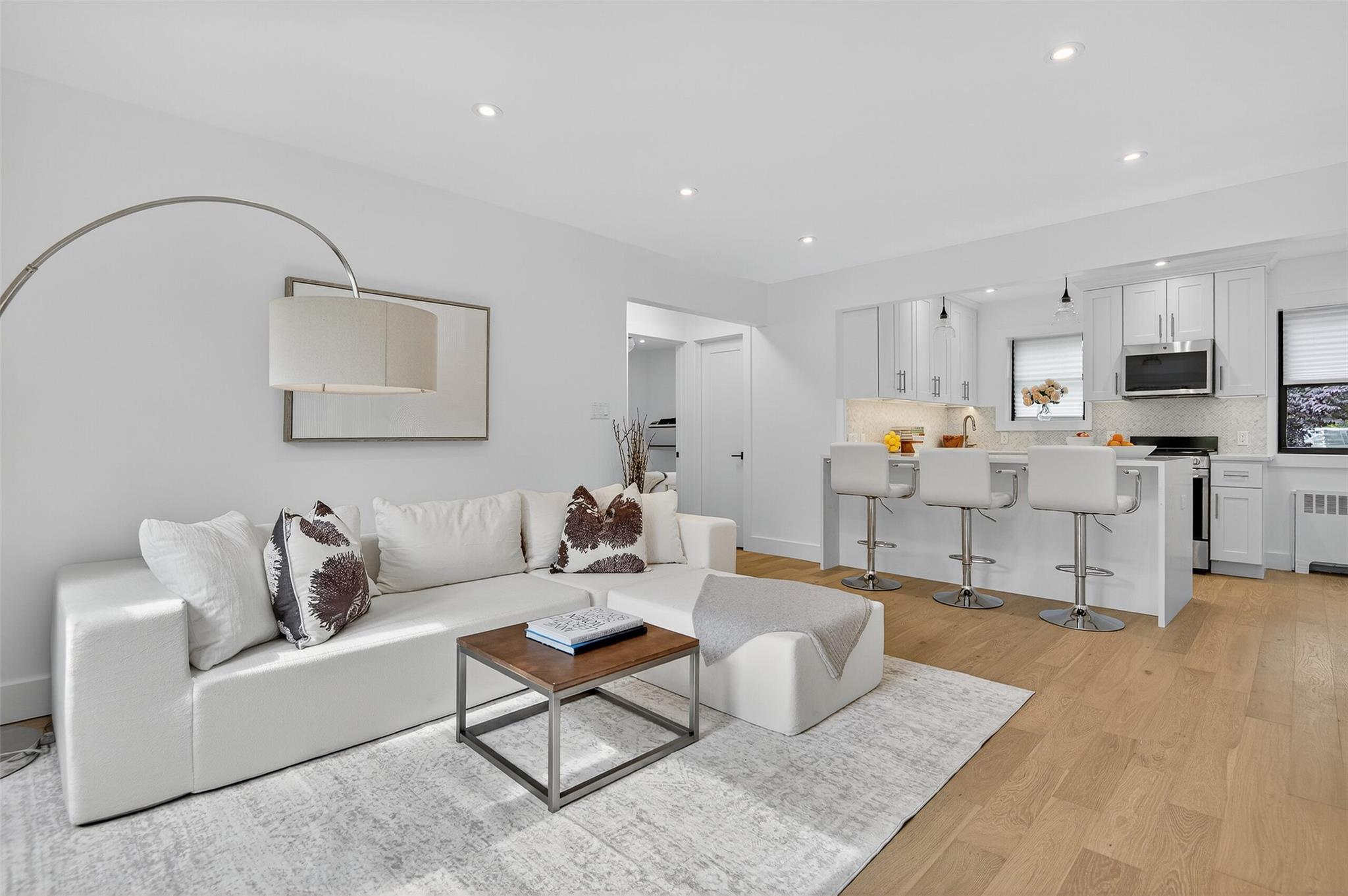 Living area with radiator heating unit, light wood-type flooring, and recessed lighting
