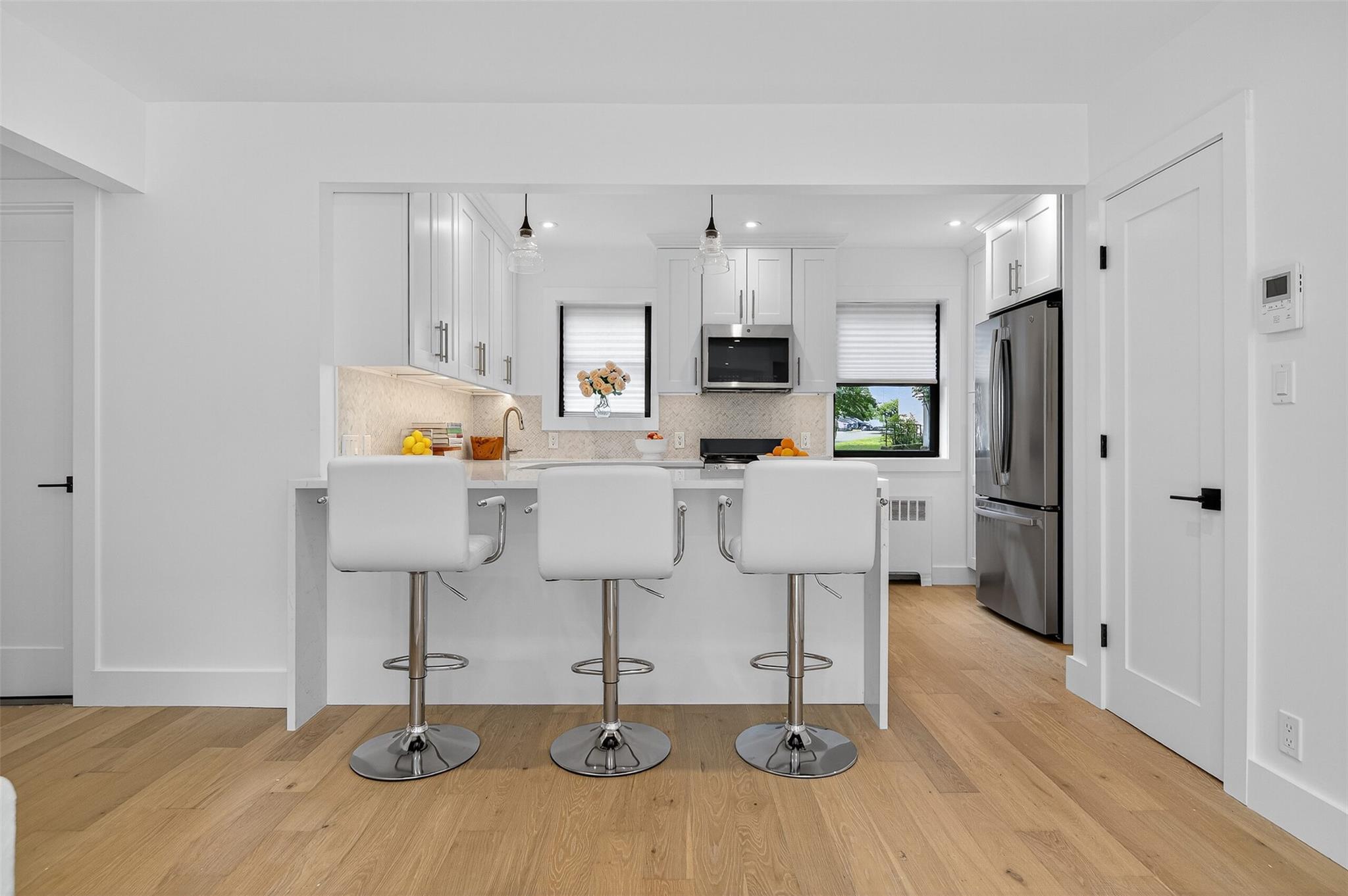 26 Terrace Circle, Unit 9C Great Neck, NY 11021 - Photo 2 of 22 Kitchen featuring appliances with stainless steel finishes, a peninsula, a kitchen bar, radiator, and recessed lighting