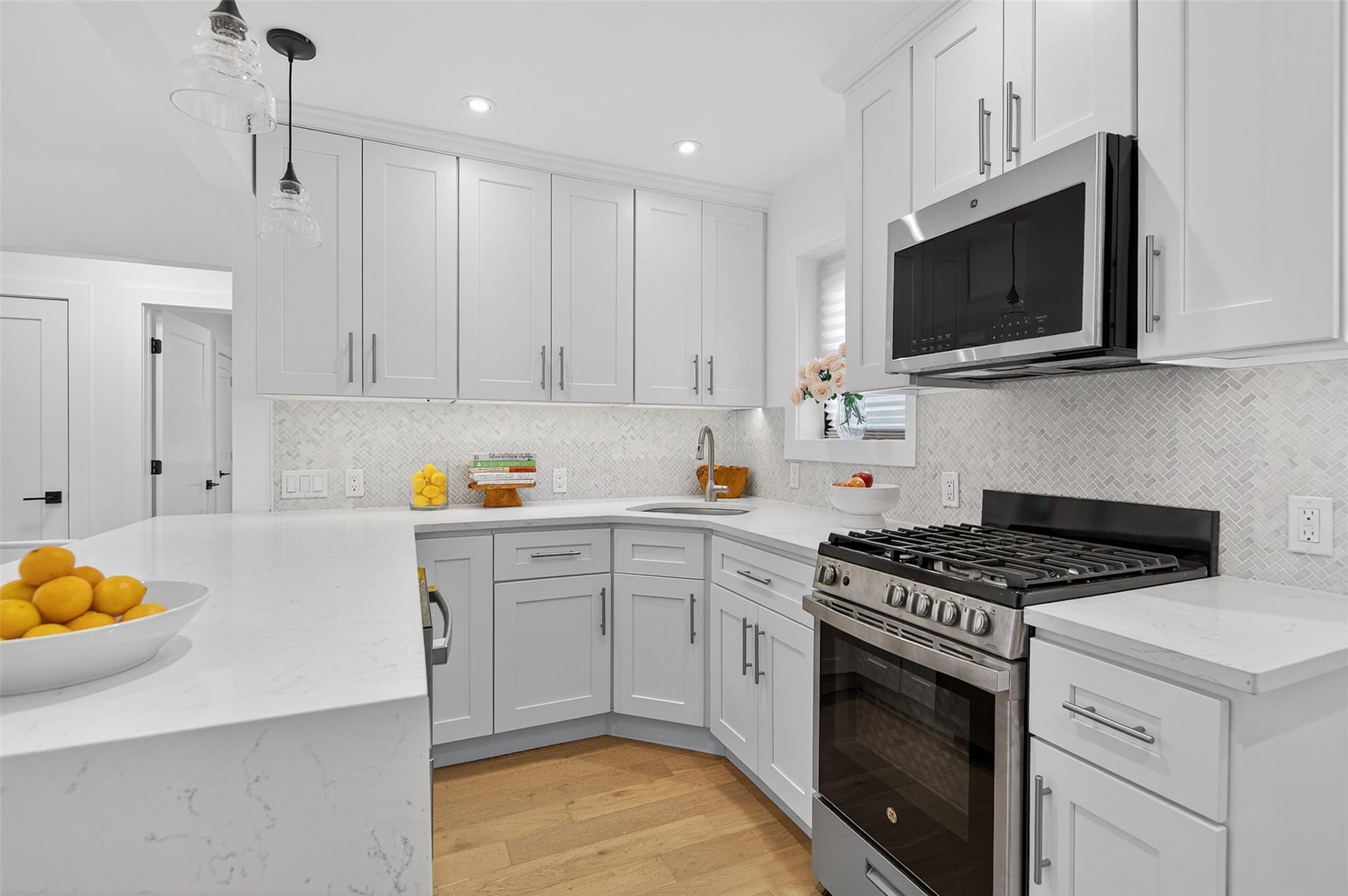 26 Terrace Circle, Unit 9C Great Neck, NY 11021 - Photo 5 of 22 Kitchen featuring appliances with stainless steel finishes, white cabinetry, light wood-style flooring, backsplash, and recessed lighting