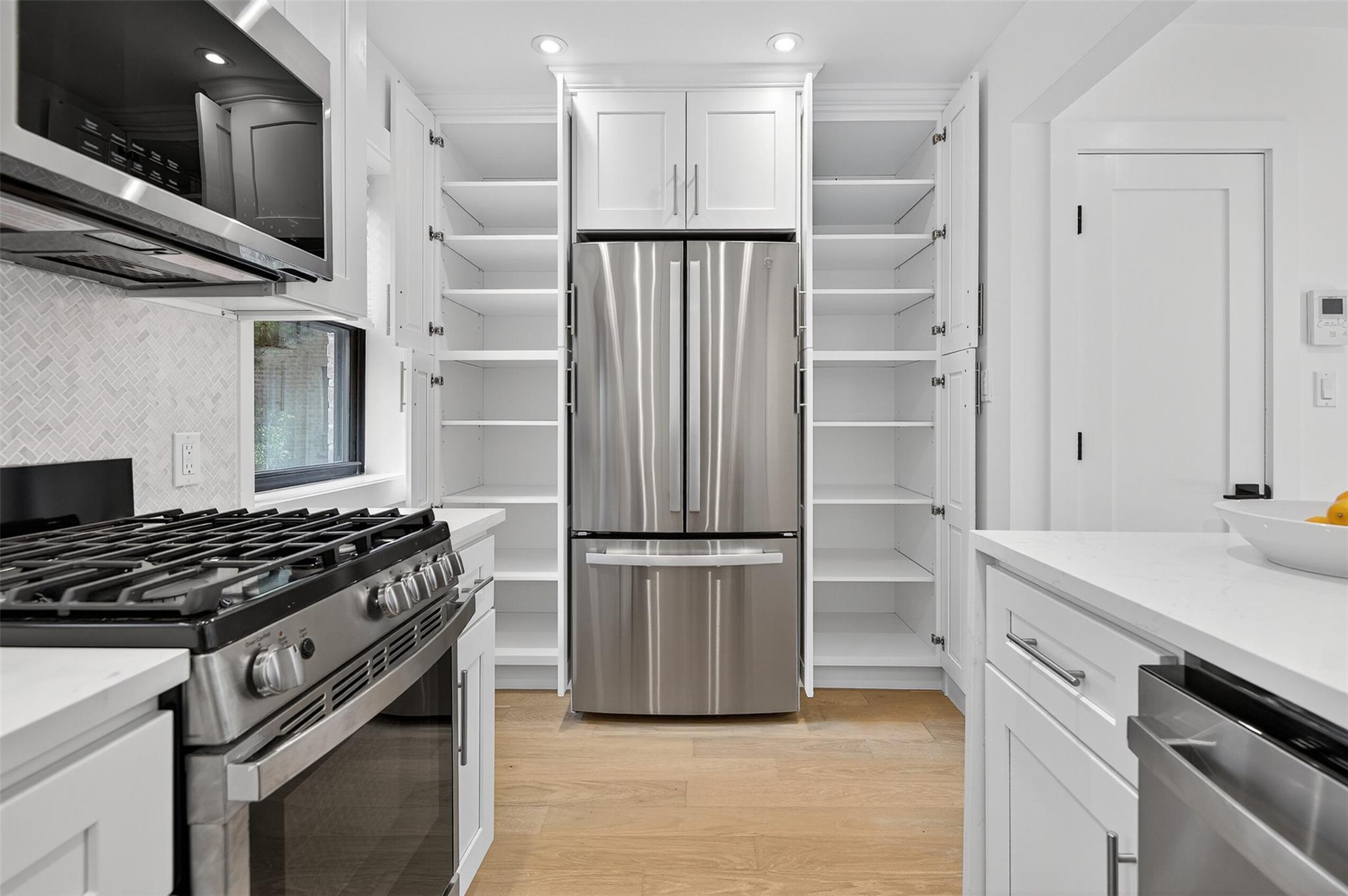 26 Terrace Circle, Unit 9C Great Neck, NY 11021 - Photo 6 of 22 Kitchen featuring stainless steel appliances, open shelves, white cabinets, decorative backsplash, and recessed lighting