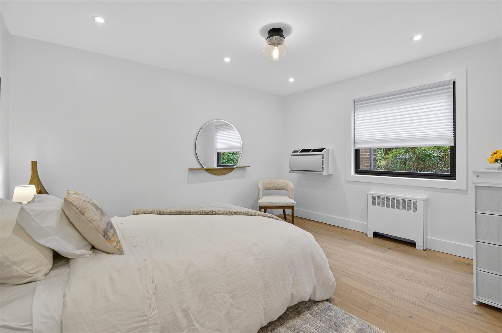 26 Terrace Circle, Unit 9C Great Neck, NY 11021 - Photo 7 of 22 Bedroom featuring radiator heating unit, light wood-type flooring, recessed lighting, and a wall mounted AC