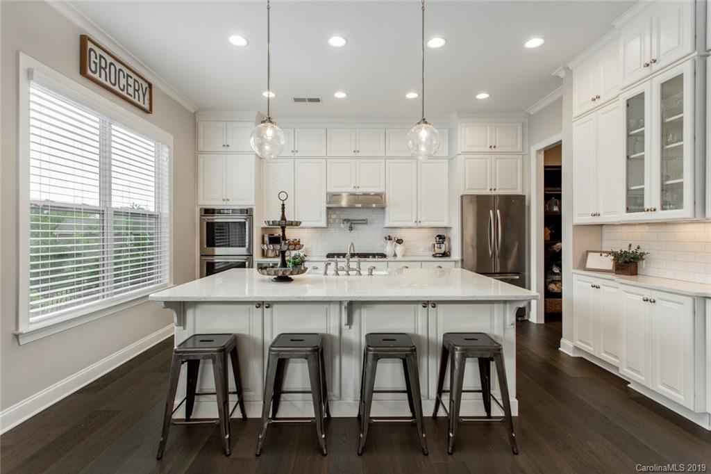 5231 Meadowcroft Way Fort Mill, SC 29708 - Photo 9 of 40 a kitchen with stainless steel appliances kitchen island granite countertop a dining table chairs and white cabinets
