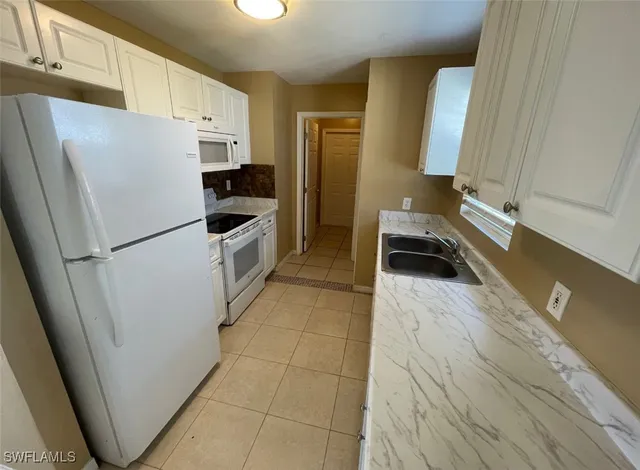 a kitchen with a refrigerator a stove top oven and cabinets