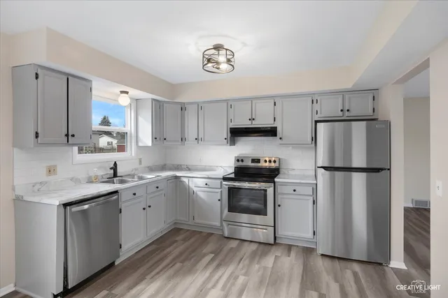 a kitchen with stainless steel appliances granite countertop a refrigerator sink and stove
