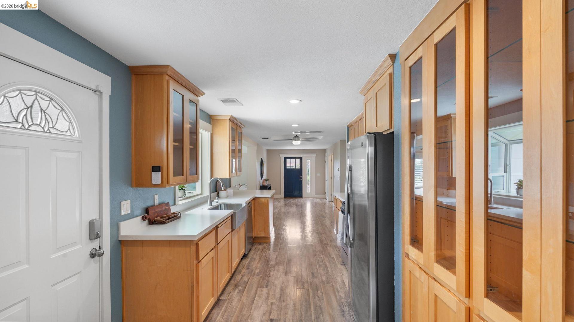 700 Brownstone Road Oakley, CA 94561 - Photo 23 of 58 Open-concept kitchen featuring wood-finish flooring, light wood cabinetry, white countertops, stainless steel appliances, and a farmhouse sink