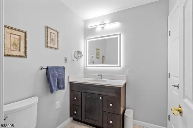 a bathroom with a granite countertop sink a mirror and a toilet