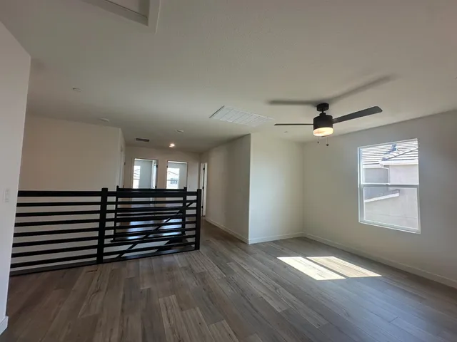 a view of empty room with wooden floor and fan