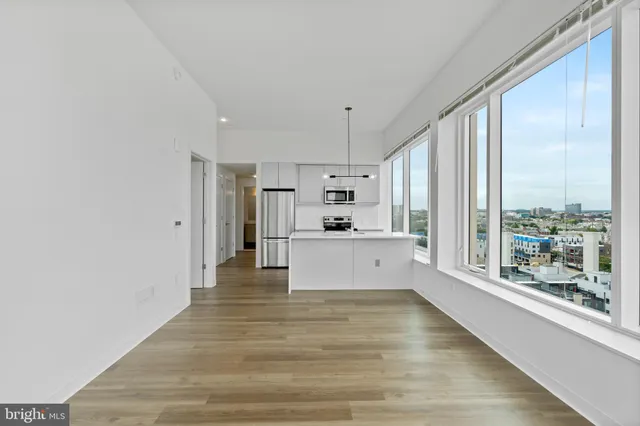 a large white kitchen with kitchen island a large window appliances and cabinets