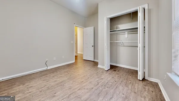 a view of an empty room with closet and wooden floor