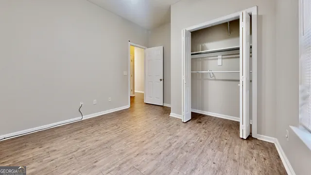 a view of an empty room with closet and wooden floor