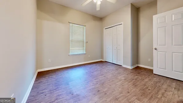 an empty room with wooden floor and windows