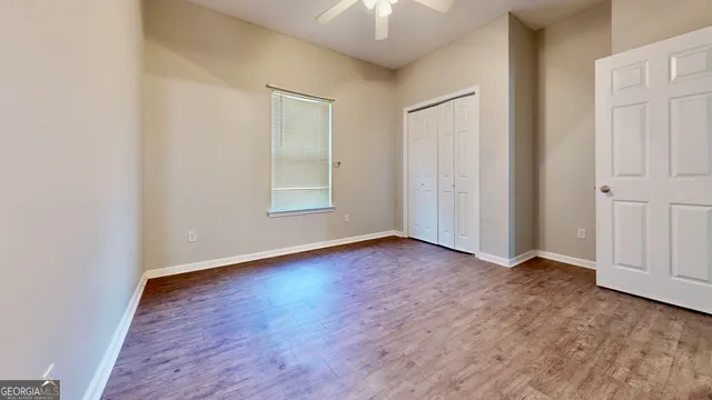 an empty room with wooden floor and windows