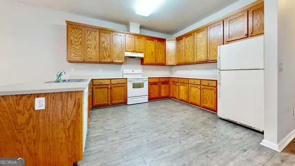 a kitchen with stainless steel appliances granite countertop wooden cabinets a refrigerator a sink a stove with wooden floor