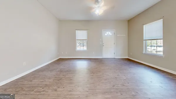 an empty room with wooden floor and windows