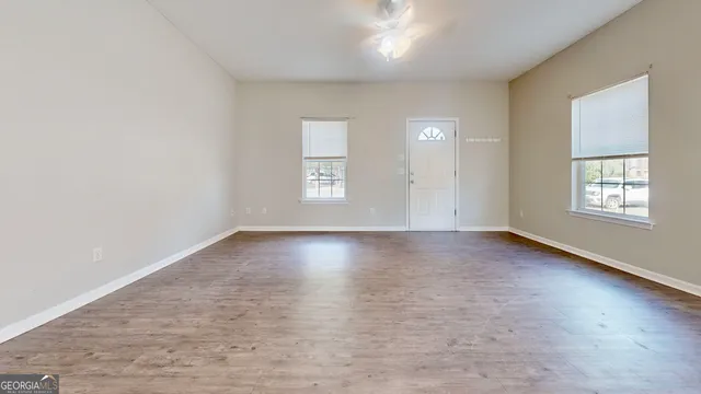 an empty room with wooden floor and windows