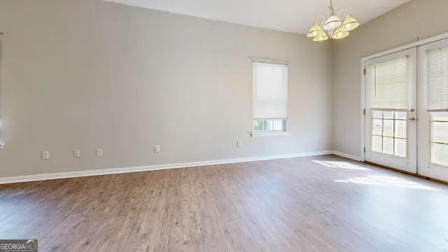 an empty room with wooden floor chandelier fan and windows