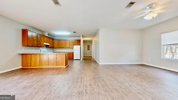 a view of kitchen and empty room with wooden floor